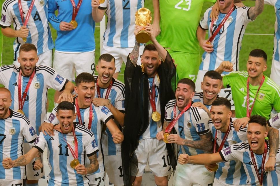 Kapten Timnas Argentina, Lionel Messi mengangkat trofi usai negaranya keluar sebagai juara Piala Dunia 2022 setelah mengalahkan Prancis pada laga final di Stadion Lusail, Qatar, Senin (19/12/2022) dini hari WIB. [Odd ANDERSEN / AFP]