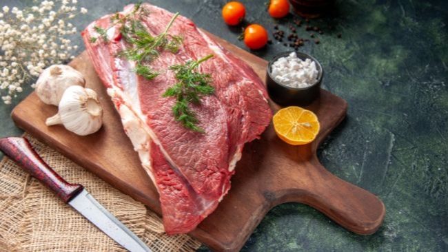 Bagian daging sapi segar pilihan tepat untuk direbus seperti sandung lamur dan iga di atas talenan kayu