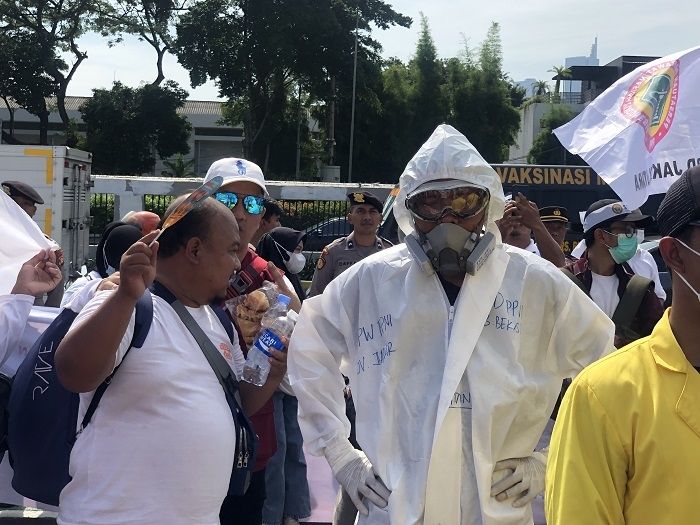 Peserta aksi tolak RUU Kesehatan Omnibus Law menggunakan hazmat di depan Gedung DPR RI, Jakarta. (Suara.com/Dea)