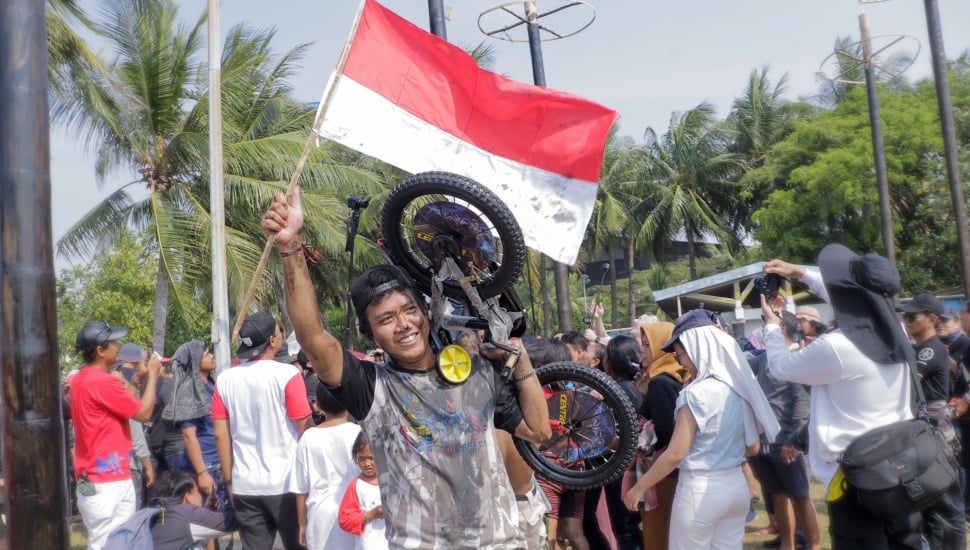 Peserta memamerkan hadiah lomba panjat pinang di Pantai Festival, Taman Impian Jaya Ancol, Jakarta, Selasa (17/8/2023). [Suara.com/Alfian Winanto]