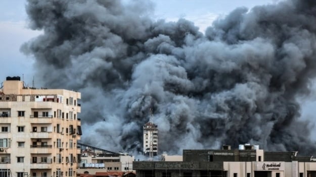 Kepulan asap membubung di atas gedung-gedung yang terkena serangan udara Israel di Kota Gaza, Palestina, Sabtu (7/10/2023).  [MAHMUD HAMS / AFP]