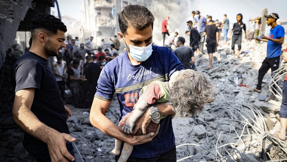 Seorang pria mengevakuasi korban anak-anak setelah serangan Israel di kamp pengungsi Bureij di Jalur Gaza, Palestina, Kamis (2/11/2023).  [Mahmud HAMS/AFP]