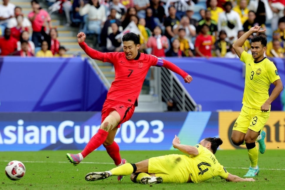 Gelandang Korea Selatan Son Heung-min berlari dengan bola melewati bek Malaysia Daniel Ting di pertandingan Grup E Piala Asia 2023 Qatar di Stadion Al-Janoub di al-Wakrah, selatan Doha, pada tanggal 25 Januari 2024.Giuseppe CACACE / AFP