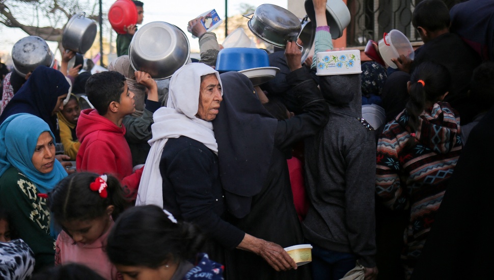 Pengungsi Palestina mengumpulkan makanan yang disumbangkan oleh sebuah badan amal untuk berbuka puasa di Rafah, Jalur Gaza Selatan, Senin (11/3/2024). [AFP]