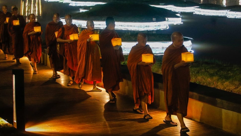 Para Bhikkhu berjalan sambil membawa lentera saat prosesi Walking Meditation di Taman Mini Indonesia Indah, Jakarta, Selasa (14/5/2024). [Suara.com/Alfian Winanto]