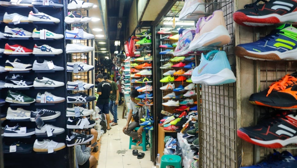 Pengunjung memlilih sepatu di Pasar Taman Puring, Jakarta, Jumat (21/6/2024). [Suara.com/Alfian Winanto]