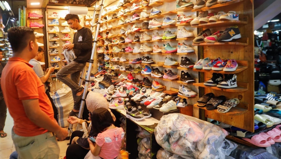 Pengunjung memlilih sepatu di Pasar Taman Puring, Jakarta, Jumat (21/6/2024). [Suara.com/Alfian Winanto]