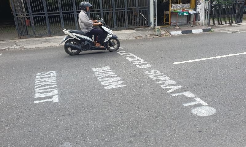 Selain dipasangi pita penggaduh atau polisi tidur, di kawasan Jalan Letjen Suprapto juga terdapat peringatan agar pengendara berhati-hati dan tidak ngebut saat melintas. Peringatan itu ditulis di badan jalan yang berbunyi Jalan Letjen Suprapto Bukan Sirkuit, Selasa (1/10/2024). [Suarajogja.id/Hiskia Andika Weadcaksana]