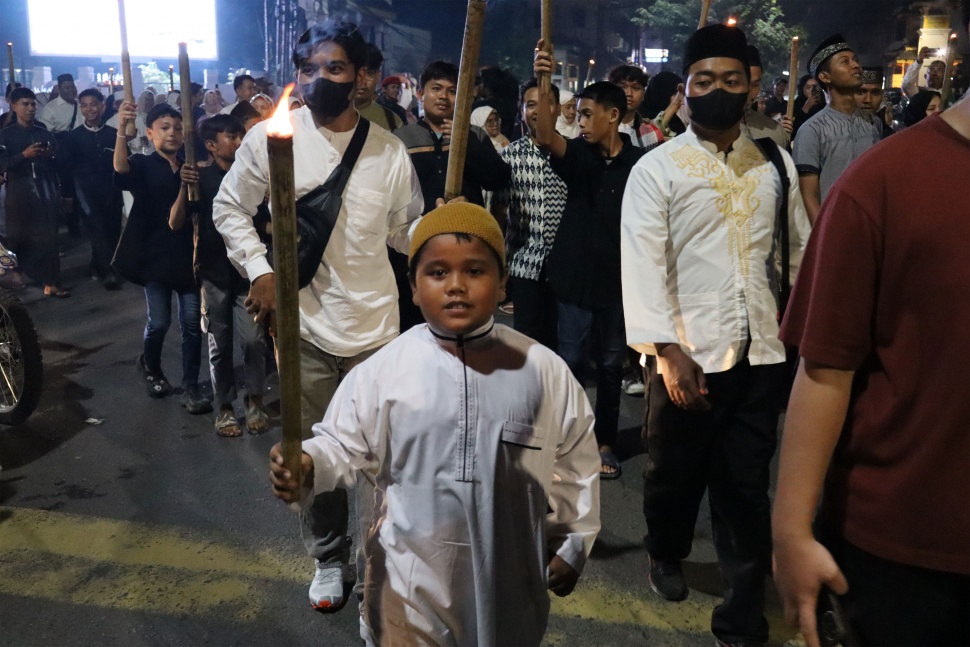 Seorang anak ikut pawai obor dalam rangka menyambut bulan suci Ramadan 2025. [Suara.com/ M.Aribowo]