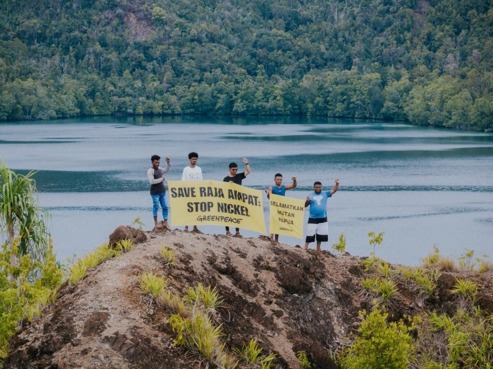 Sejumlah warga Desa Manyaifun bersama aktivis Greenpeace Indonesia berpose untuk foto bersama dengan spanduk bertuliskan ‘Selamatkan Raja Ampat, Stop Nikel’ dan ‘Selamatkan Hutan Papua’, dengan Desa Manyaifun dan perbukitan Pulau Batang Pele di latar belakang. Pulau Batang Pele merupakan destinasi wisata yang juga masuk dalam kawasan hutan lindung dan menjadi bagian dari UNESCO Global Geopark. Saat ini, izin usaha pertambangan nikel tengah diajukan untuk pulau tersebut oleh PT Mulia Reymond Perkasa, yang mencakup wilayah konsesi seluas 2.193 hektare, yang meliputi Desa Manyaifun dan Pulau Batang Pele. (Dok: Alif R Nouddy Korua / Greenpeace)