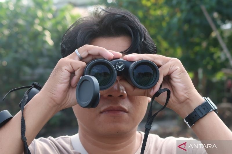 Seorang warga menggunakan teropong melihat burung-burung migran yang mencari pakan dalam kegiatan Lombok Bird Walk di kawasan muara Pantai Ampenan, Kota Mataram, Nusa Tenggara Barat, Minggu (22/6/2025). (ANTARA/Sugiharto Purnama)