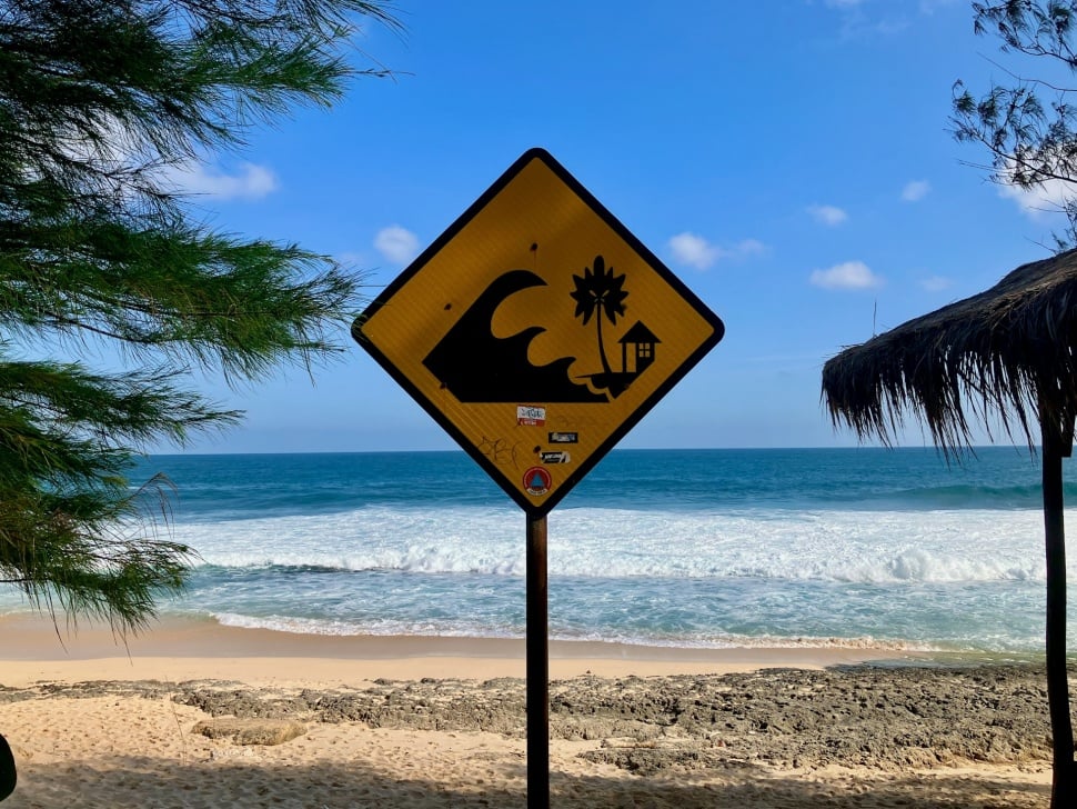 A clear and informative tsunami warning sign at Pantai Bercak beach in Pacitan, East Java, Indonesia. The sign, set against the backdrop of the ocean, provides critical safety information for beachgoers. [Unsplash/Jeffrey thuman]