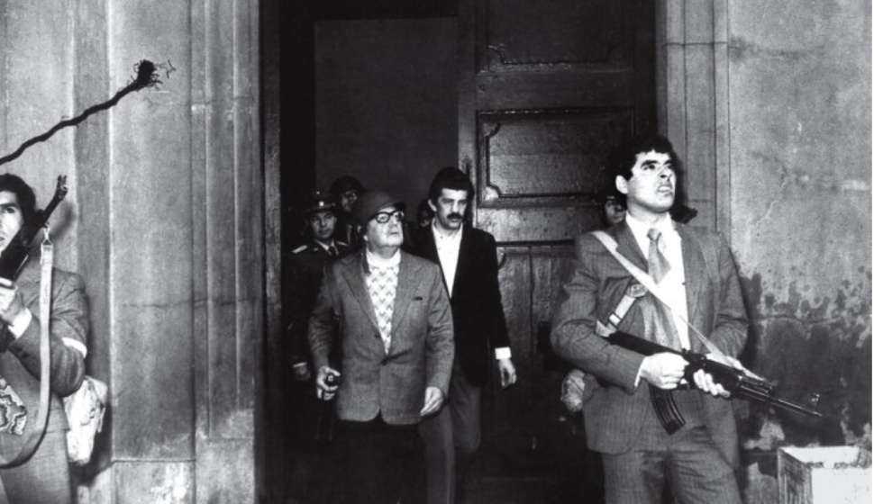 Presiden Chile Salvador Allende (memakai helm) yang menggenggam pistol hadiah dari pemimpin Kuba Fidel Castro, dikawal pengawal setianya, tetap melawan saat istana kepresidenan dikepung militer dukungan AS, 11 September 2073. [getty image]