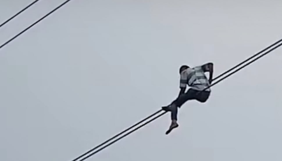 Seorang pria bernama Sukardi nekat melakukan aksi berbahaya dengan bergelantungan di kabel udara di Jalan Gatot Subroto, Karet Kuningan, Setiabudi, Jakarta Selatan. Aksi tersebut viral di media sosial. [Bidik layar]