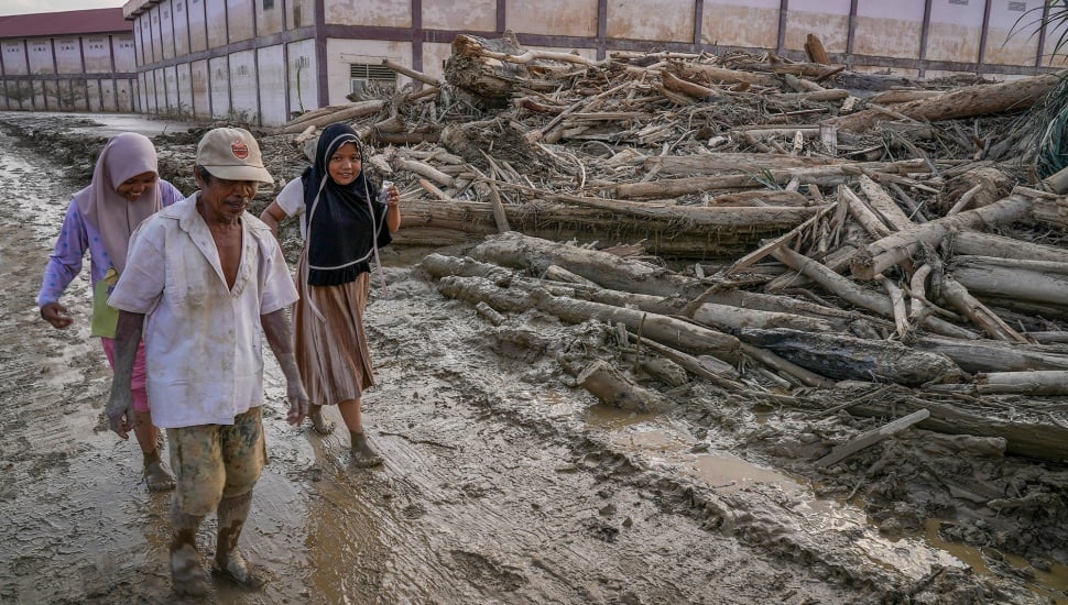 Sejumlah warga melewati kayu-kayu yang memenuhi area Pondok Pesantren Darul Mukhlishin pascabanjir bandang di Desa Tanjung Karang, Karang Baru, Kabupaten Aceh Tamiang, Aceh, Jumat (5/12/2025). [ANTARA FOTO/Erlangga Bregas Prakoso/app/foc]