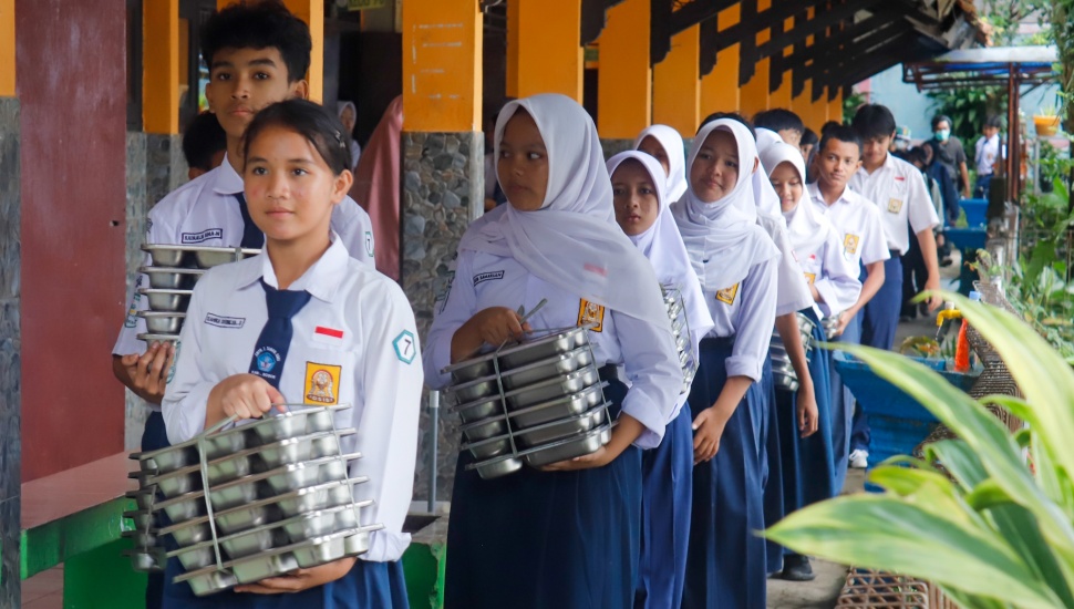 Para siswa membawa menu Makan Bergizi Gratis (MBG) untuk dibagikan ke kelas masing-masinh di SMPN 1 Tamansari, Bogor, Jawa Barat, Selasa (16/12/2025). [Suara.com/Alfian Winanto]
