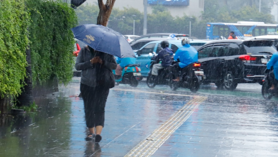 Sejumlah warga beraktivitas saat turun hujan di kawasan Bundaran HI, Jakarta, Selasa (13/1/2026). [Suara.com/Alfian Winanto]