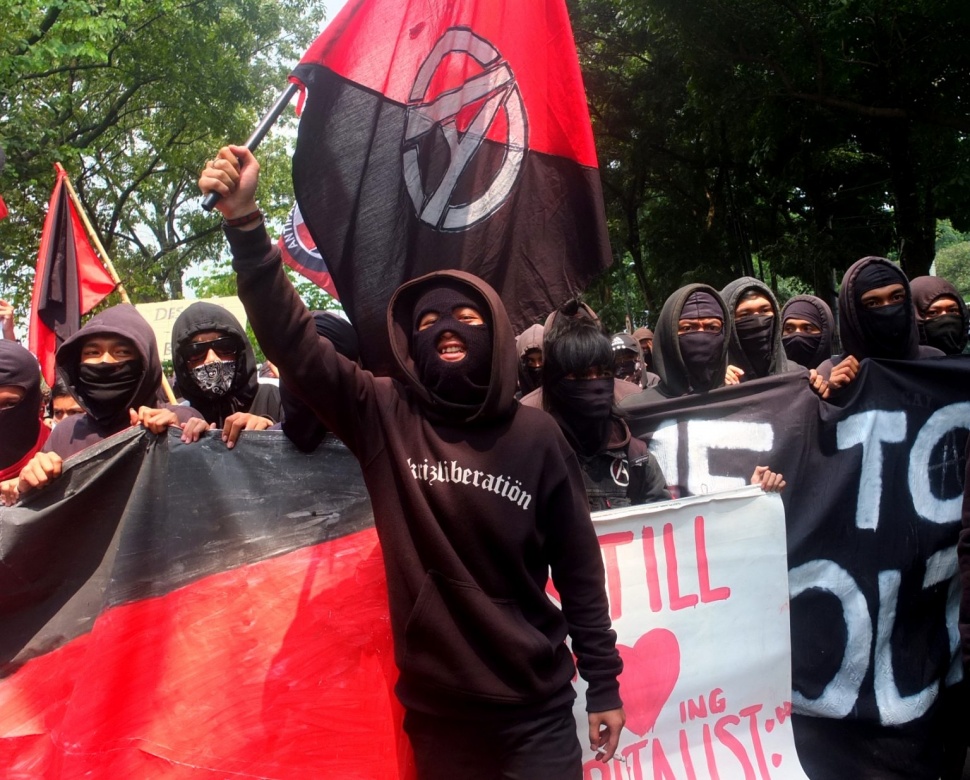 Salah satu kaum Anarkis tengah mengibarkan bendera. [Frans Ari Prasetyo]