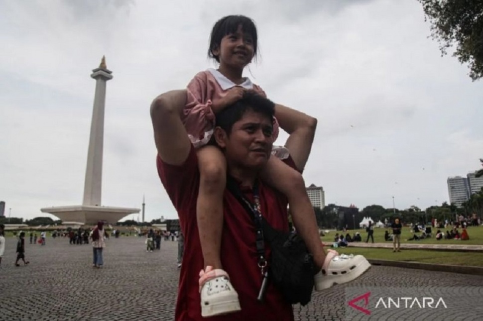 Salah satu pengunjung menggendong anaknya saat berwisata di Monumen Nasional (Monas), Jakarta, Senin (23/3/2026). ANTARA FOTO/Darryl Ramadhan.