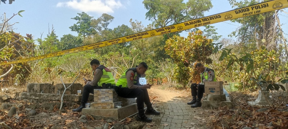 Pihak kepolisian melakukan penjagaan di sekitar Tempat Pemakaman Umum (TPU) Bantaragung, tempat peristirahatan terakhir Sutrimo, saat petugas tengah melakukan proses ekshumasi (pembongkaran makam). (Suara.com/Adi Kurniawan)