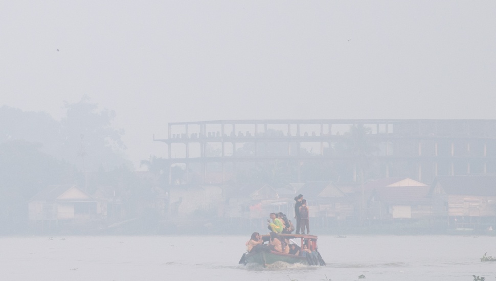 Sejumlah pelajar berangkat sekolah menggunakan perahu tradisional melewati kawasan yang diselimuti kabut asap di Sungai Ogan, Palembang, Sumatera Selatan, Kamis (13/8/2026). [ANTARA FOTO/Nova Wahyudi/YU]