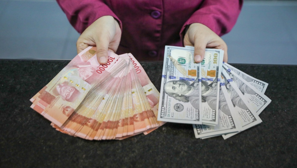 Petugas salah satu tempat penukaran mata uang asing menunjukkan uang rupiah dan dollar AS di Jakarta, Selasa (29/9/2026). [Suara.com/Alfian Winanto]