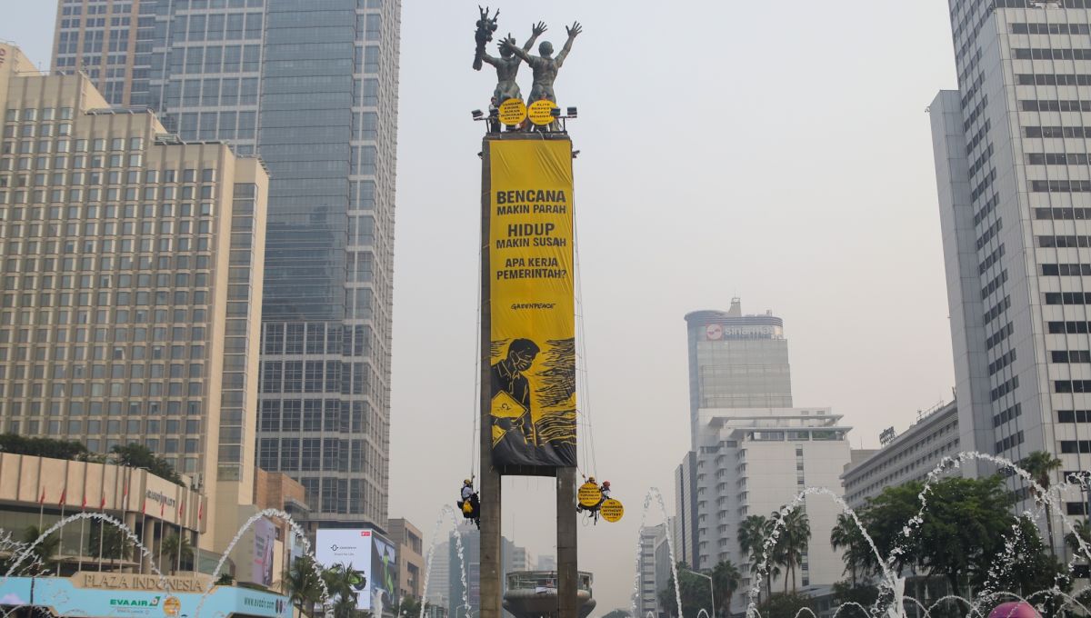 Sejumlah aktifis Greenpeace membentangkan spanduk yang bertema krisis iklim di Bundaran HI, Jakarta, Selasa (20/10/2026). [Suara.com/Alfian Winanto]