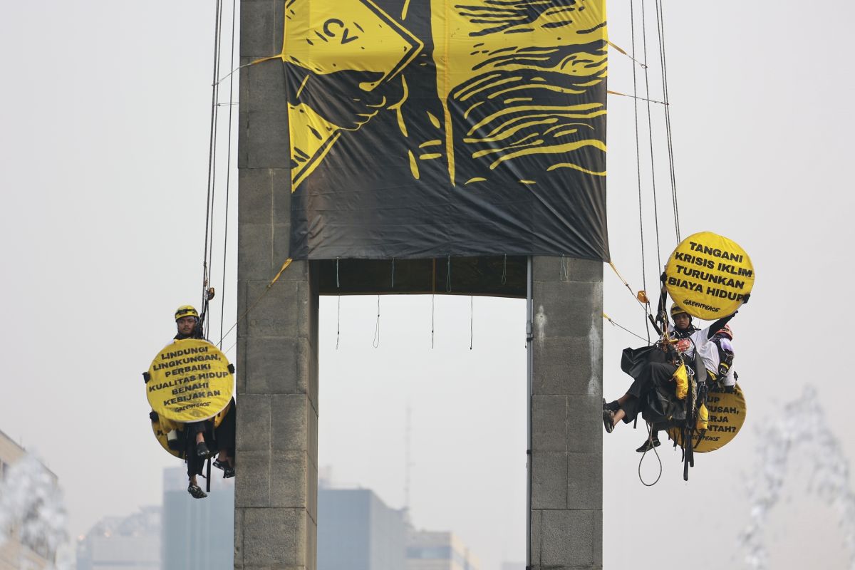Sejumlah ktivis Greenpeace Indonesia membentangkan dua spanduk raksasa dari puncak Patung Selamat Datang di Bundaran Hotel Indonesia, Jakarta Pusat, Selasa (20/10/2026). Spanduk itu berisi tulisan protes terhadap pemerintahan Prabowo-Subianto yang membiarkan krisis ekologi serta krisis ekonomi. [Dhemas Reviyanto/Greenpeace]