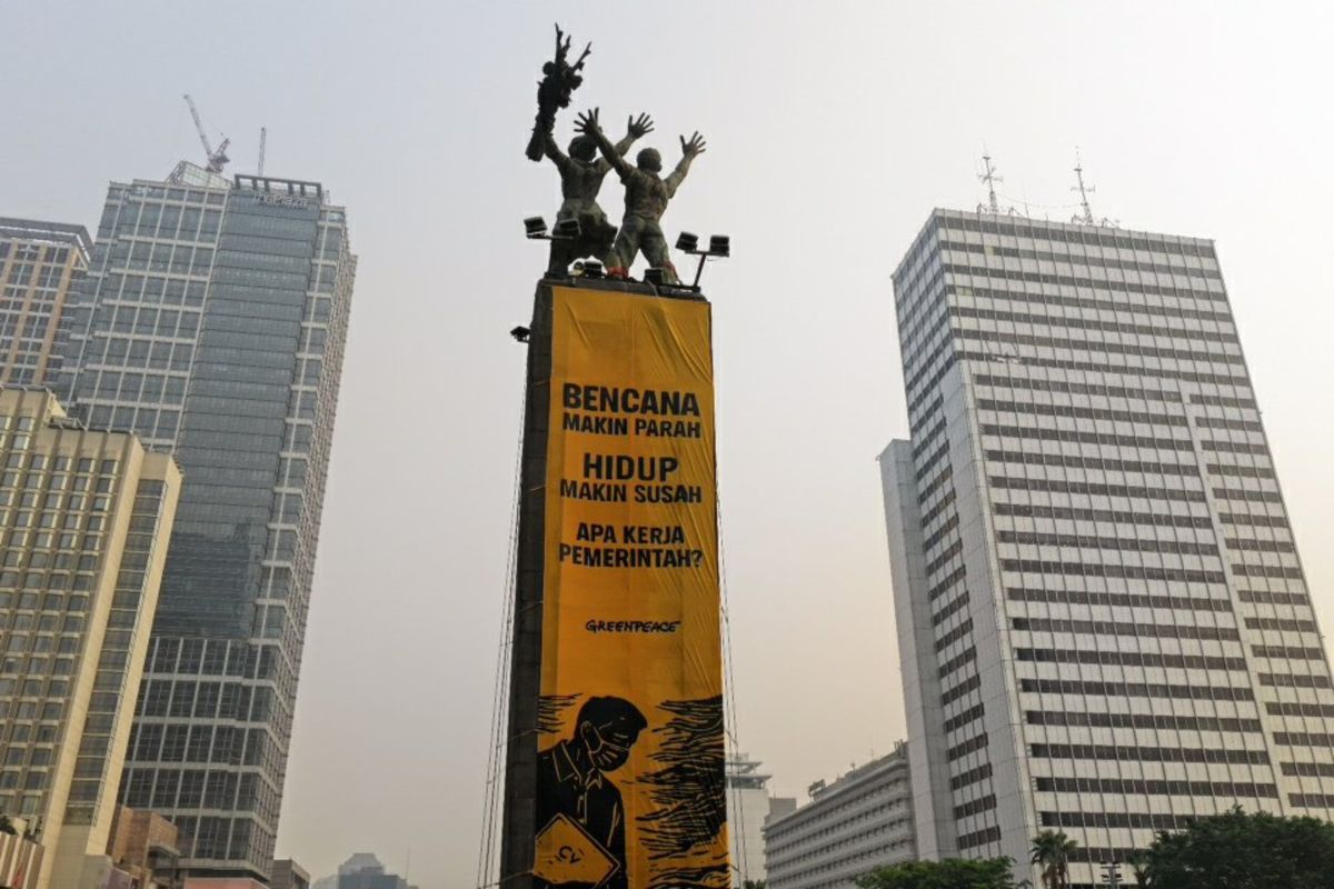 Sejumlah ktivis Greenpeace Indonesia membentangkan dua spanduk raksasa dari puncak Patung Selamat Datang di Bundaran Hotel Indonesia, Jakarta Pusat, Selasa (20/10/2026). Spanduk itu berisi tulisan protes terhadap pemerintahan Prabowo-Subianto yang membiarkan krisis ekologi serta krisis ekonomi. [Odi Putera/Greenpeace]