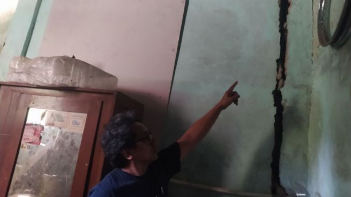 Heru Agam, Ketua RT 04/13 Desa Laksanamekar, Kecamatan Padalarang, Kabupaten Bandung Barat Menunjukan Salah Satu Sudut Rumahnya yang Menganga Sejak Tahun 2019 Usai Adanya Blasting Tunnel 11 Kereta Cep [Ferry/Suara,com]