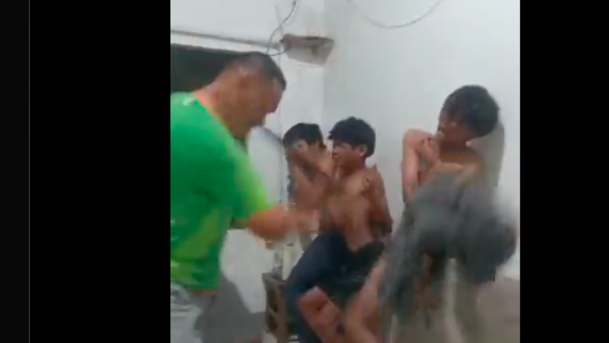 Seorang pria berambut cepak tengah melakukan penyiksaan terhadap tiga orang pemuda.