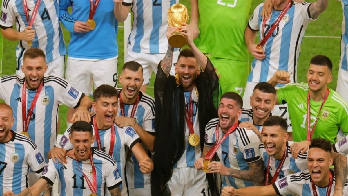 Kapten Timnas Argentina, Lionel Messi mengangkat piala juara dunia dengan menggunakan jubah ciri khas TImur Tengah, yang diberikan kepadanya saat menerima piala dari Presiden FIFA [Foto: Suara.com / Odd ANDERSEN / AFP]