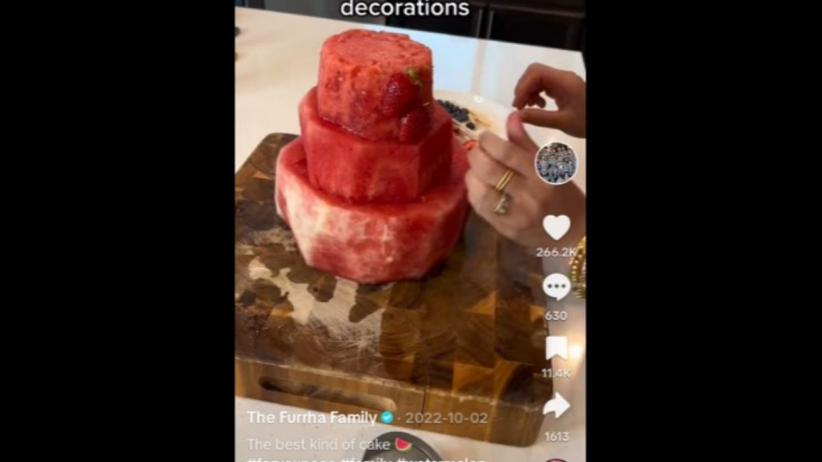 Cake semangka dipersiapkan di talenan, buah bulat dipotong dan dibentuk mirip cake [[screenshot TikTok The Furrha Family].]