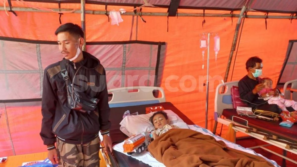 Azka (5), seorang anak yang selamat dari reruntuhan puing rumahnya, akibat gempa Cianjur, hanya bisa terbaring di atas kasur rumah sakit dalam tenda darurat di halaman Rumah Sakit Umum Daerah Sayang Cianjur. [Suara.com/Faqih]