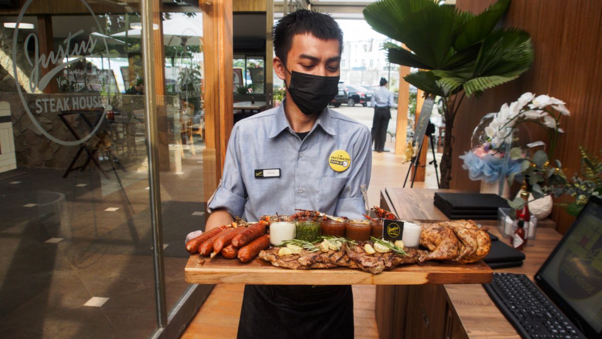 Pelayan membawa menu Premium Family Set di Justus Steakhouse Alam Sutera [SuaraSerang/Anhar Rizki Affandi]