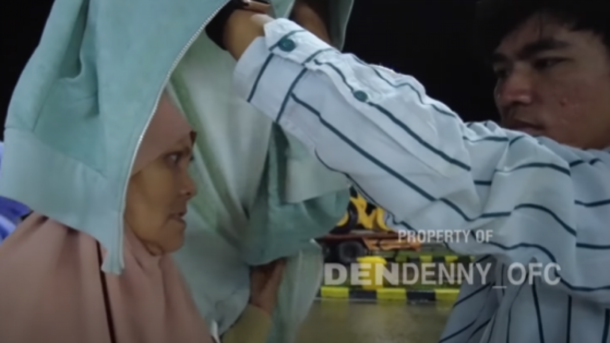 Tiko melindungi Ibu Eny dari rintik hujan di rest area dalam perjalanan menuju Madiun [YouTube/DenDenny]