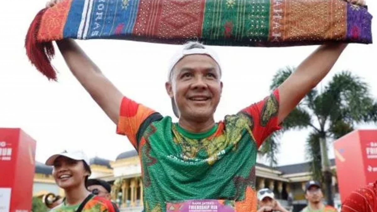 Gubernur Jawa Tengah Ganjar Pranowo mengangkat ulos dalam kegiatan Bank Jateng Friendship Run Borobudur Marathon 2022 di Medan. [Suara.com]